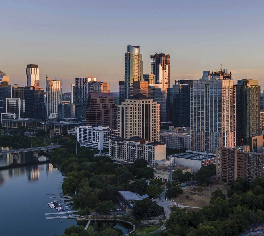 Panoramic view of a metropolitan city skyline along a riverfront at dusk